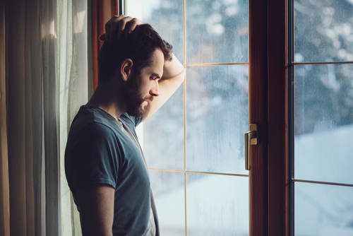 Upset man standing in window after gambling losses